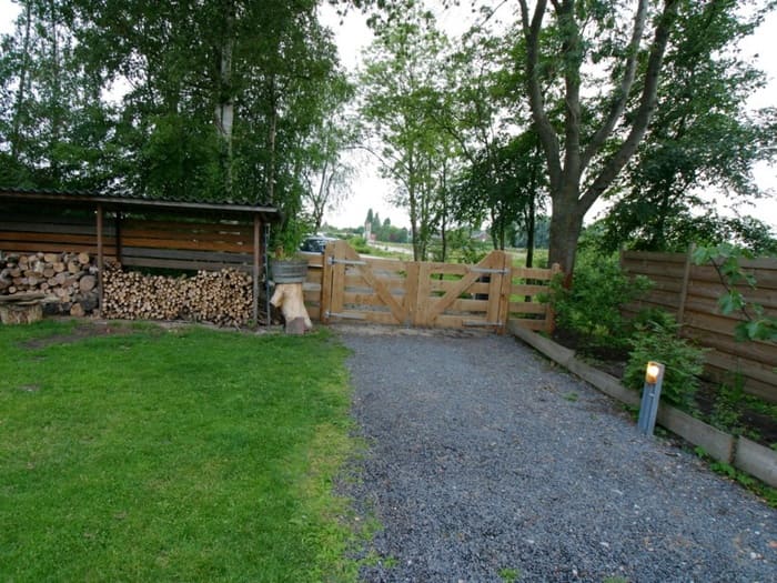 Handgemaakt houten landhek van eikenhout als landelijke erfafscheiding bij een oprit met grindpad
