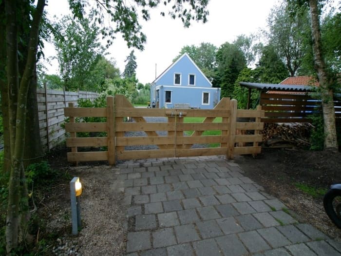Houten landhek op maat met dubbele draaideuren als landelijke erfafscheiding bij een vrijstaande woning