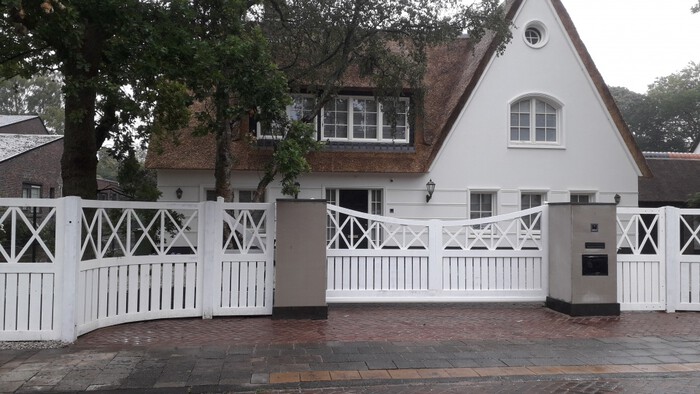 Houten poorten in Emmen met wit hekwerk en dubbele draaipoort bij karakteristieke woning