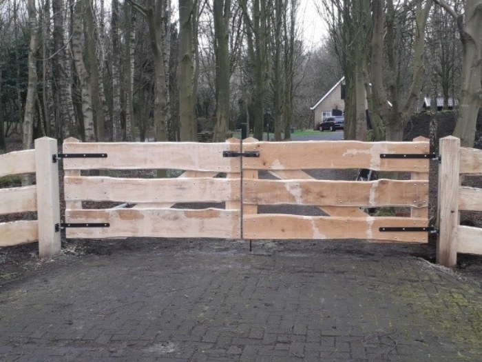 Landelijke maatwerk houten poort in Gelderland tussen houten erfpalen en bosrijke omgeving