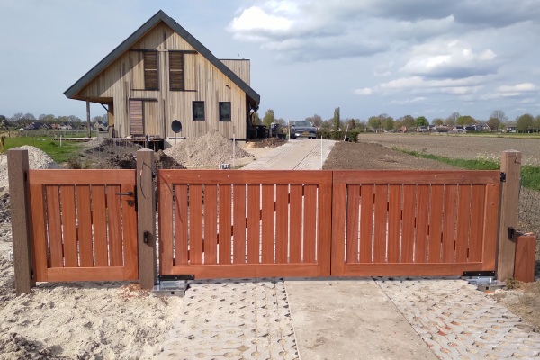 Padouk hek met looppoort en dubbele toegangspoort bij een landelijke woning.